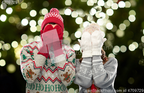 Image of couple in ugly sweaters and mittens on christmas
