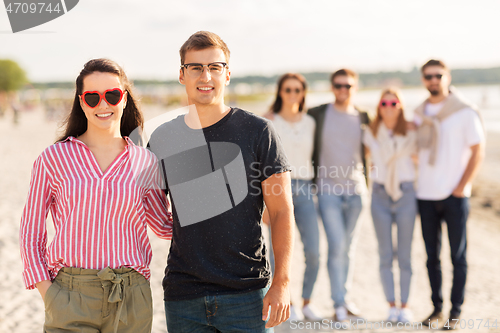 Image of happy friends walking along summer beach