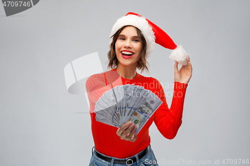 Image of happy woman in santa hat with money on christmas