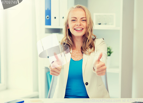 Image of happy businesswoman showing thumbs up at office