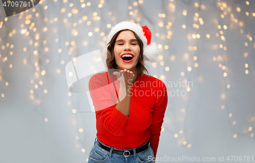 Image of woman in santa hat sending air kiss on christmas