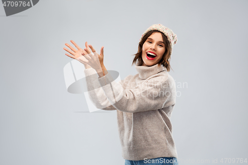 Image of woman in hat and sweater holding something