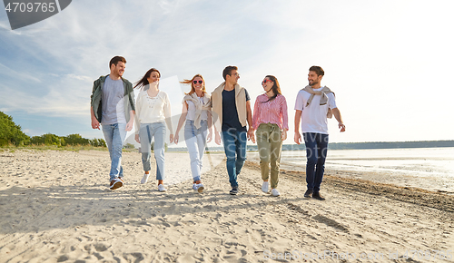 Image of happy friends walking along summer beach