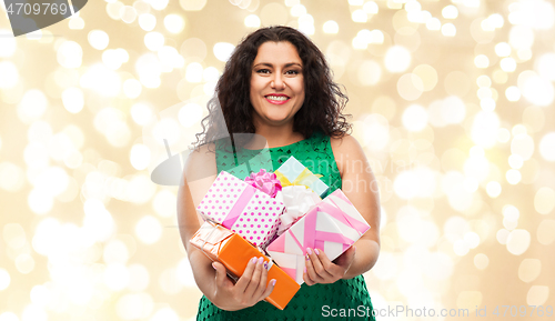 Image of happy woman holding gift boxes over lights