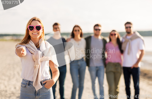 Image of woman with friends on beach pointing to you