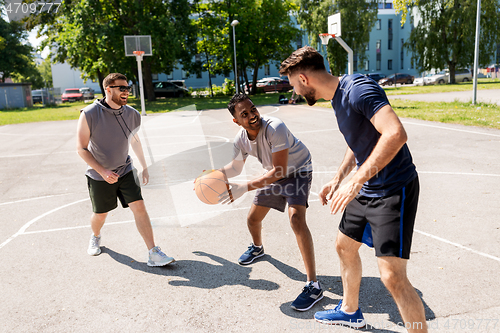 Image of group of male friends playing street basketball