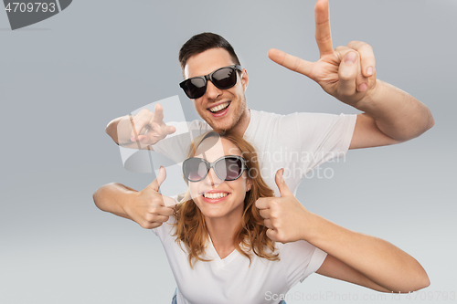 Image of happy couple in sunglasses showing peace