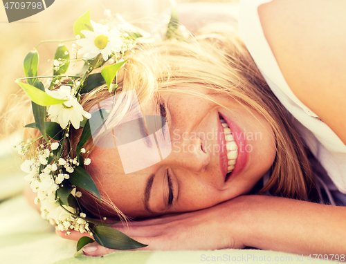 Image of happy woman in wreath of flowers lying