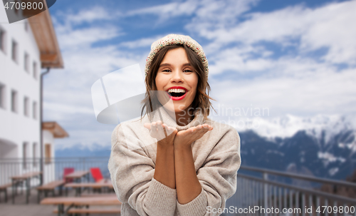 Image of woman in winter hat sending air kiss at ski resort