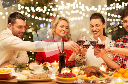 Image of happy friends drinking red wine at christmas party