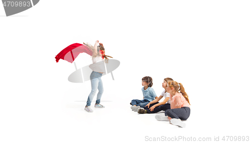 Image of Child pretending to be a superhero with her friends sitting around