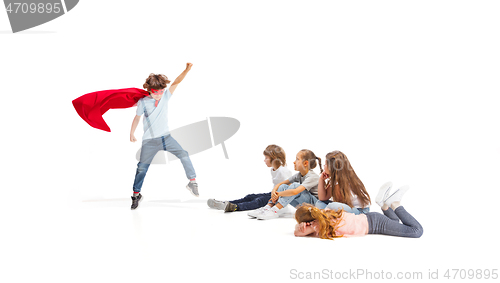 Image of Child pretending to be a superhero with his friends sitting around