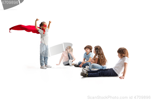 Image of Child pretending to be a superhero with her friends sitting around