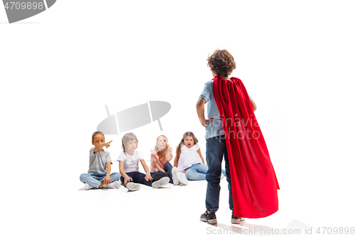 Image of Child pretending to be a superhero with his friends sitting around