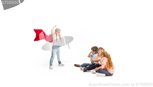 Image of Child pretending to be a superhero with her friends sitting around