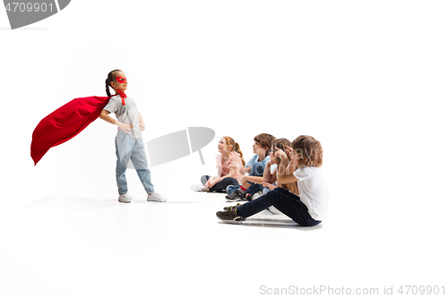 Image of Child pretending to be a superhero with her friends sitting around