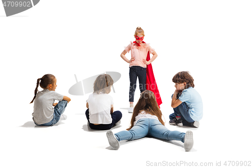 Image of Child pretending to be a superhero with her friends sitting around