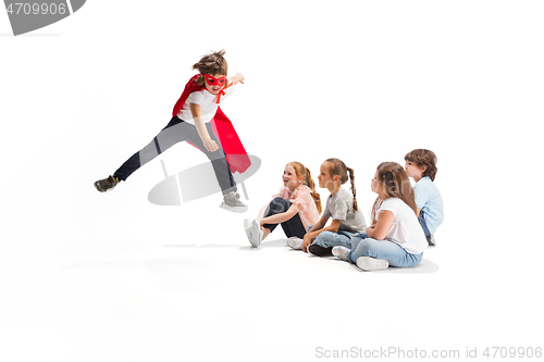 Image of Child pretending to be a superhero with his friends sitting around