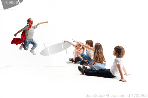 Image of Child pretending to be a superhero with her friends sitting around