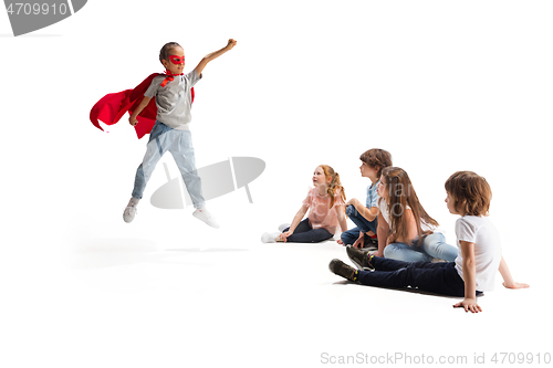 Image of Child pretending to be a superhero with her friends sitting around