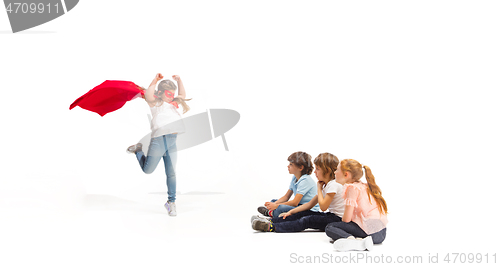 Image of Child pretending to be a superhero with her friends sitting around