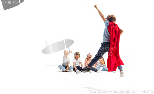 Image of Child pretending to be a superhero with his friends sitting around