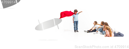 Image of Child pretending to be a superhero with his friends sitting around