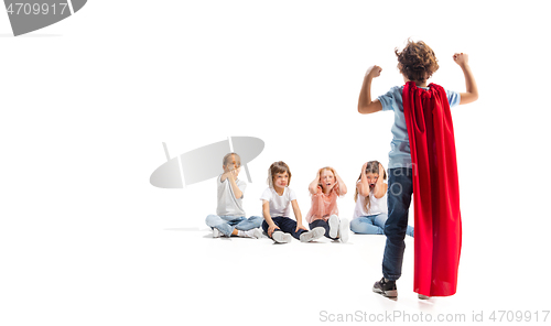 Image of Child pretending to be a superhero with his friends sitting around