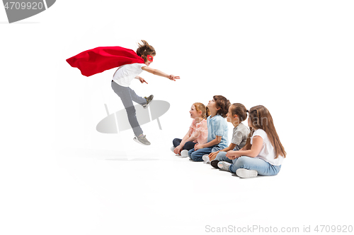 Image of Child pretending to be a superhero with his friends sitting around