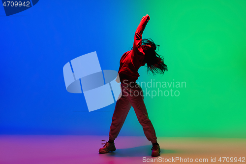 Image of Stylish sportive girl dancing hip-hop in stylish clothes on colorful background at dance hall in neon light. Youth culture, movement, style and fashion, action.