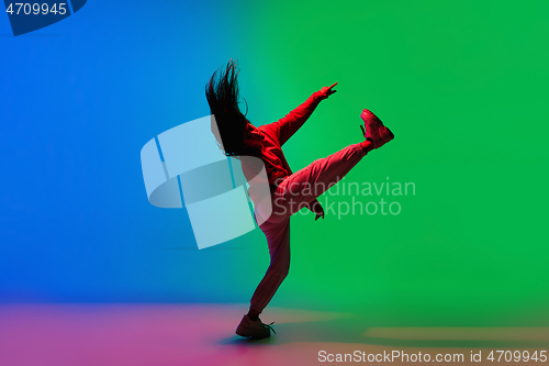 Image of Stylish sportive girl dancing hip-hop in stylish clothes on colorful background at dance hall in neon light. Youth culture, movement, style and fashion, action.