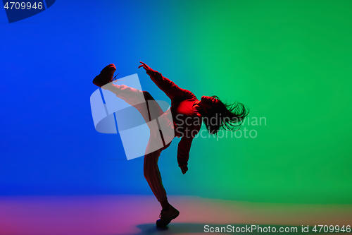 Image of Stylish sportive girl dancing hip-hop in stylish clothes on colorful background at dance hall in neon light. Youth culture, movement, style and fashion, action.