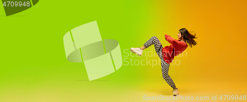 Image of Stylish sportive girl dancing hip-hop in stylish clothes on colorful background at dance hall in neon light. Youth culture, movement, style and fashion, action.