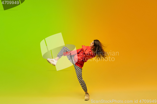 Image of Stylish sportive girl dancing hip-hop in stylish clothes on colorful background at dance hall in neon light. Youth culture, movement, style and fashion, action.