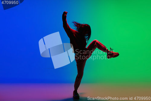 Image of Stylish sportive girl dancing hip-hop in stylish clothes on colorful background at dance hall in neon light. Youth culture, movement, style and fashion, action.