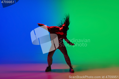 Image of Stylish sportive girl dancing hip-hop in stylish clothes on colorful background at dance hall in neon light. Youth culture, movement, style and fashion, action.