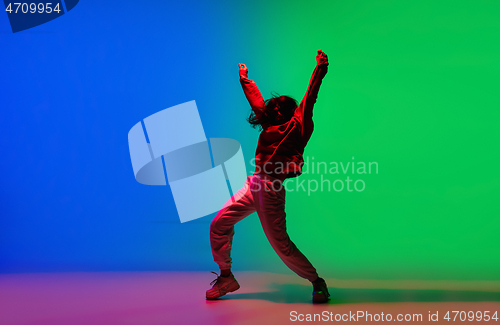 Image of Stylish sportive girl dancing hip-hop in stylish clothes on colorful background at dance hall in neon light. Youth culture, movement, style and fashion, action.