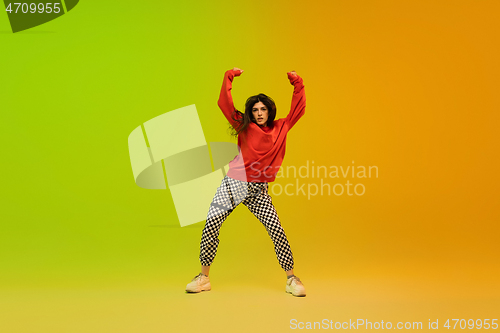 Image of Stylish sportive girl dancing hip-hop in stylish clothes on colorful background at dance hall in neon light. Youth culture, movement, style and fashion, action.