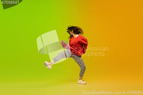 Image of Stylish sportive girl dancing hip-hop in stylish clothes on colorful background at dance hall in neon light. Youth culture, movement, style and fashion, action.