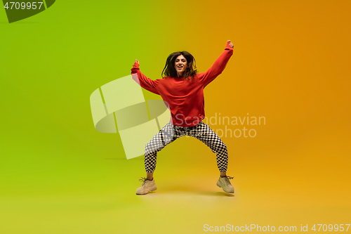 Image of Stylish sportive girl dancing hip-hop in stylish clothes on colorful background at dance hall in neon light. Youth culture, movement, style and fashion, action.