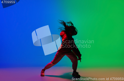 Image of Stylish sportive girl dancing hip-hop in stylish clothes on colorful background at dance hall in neon light. Youth culture, movement, style and fashion, action.