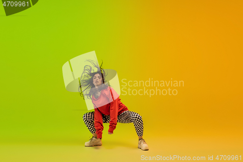 Image of Stylish sportive girl dancing hip-hop in stylish clothes on colorful background at dance hall in neon light. Youth culture, movement, style and fashion, action.