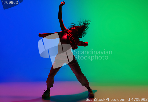 Image of Stylish sportive girl dancing hip-hop in stylish clothes on colorful background at dance hall in neon light. Youth culture, movement, style and fashion, action.