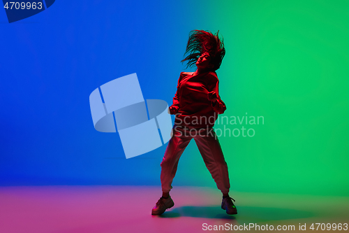 Image of Stylish sportive girl dancing hip-hop in stylish clothes on colorful background at dance hall in neon light. Youth culture, movement, style and fashion, action.