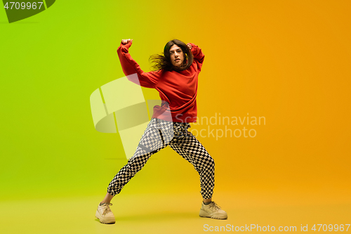 Image of Stylish sportive girl dancing hip-hop in stylish clothes on colorful background at dance hall in neon light. Youth culture, movement, style and fashion, action.