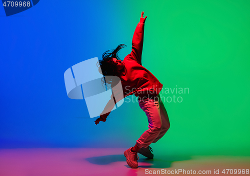 Image of Stylish sportive girl dancing hip-hop in stylish clothes on colorful background at dance hall in neon light. Youth culture, movement, style and fashion, action.