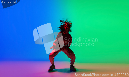 Image of Stylish sportive girl dancing hip-hop in stylish clothes on colorful background at dance hall in neon light. Youth culture, movement, style and fashion, action.