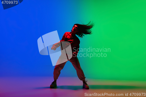 Image of Stylish sportive girl dancing hip-hop in stylish clothes on colorful background at dance hall in neon light. Youth culture, movement, style and fashion, action.