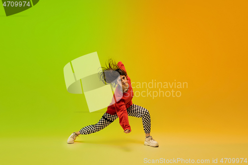 Image of Stylish sportive girl dancing hip-hop in stylish clothes on colorful background at dance hall in neon light. Youth culture, movement, style and fashion, action.