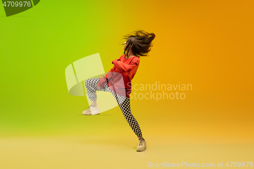 Image of Stylish sportive girl dancing hip-hop in stylish clothes on colorful background at dance hall in neon light. Youth culture, movement, style and fashion, action.